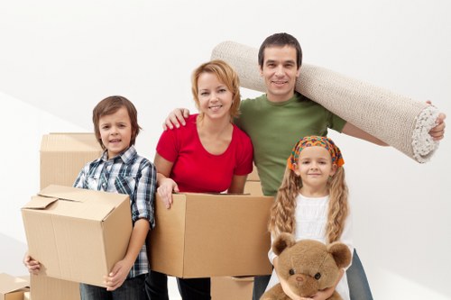 Local removals team carrying furniture through a residential street in West Hampstead