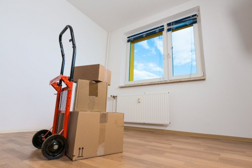 Local piano movers navigating a West Hampstead flat stairway with protective equipment